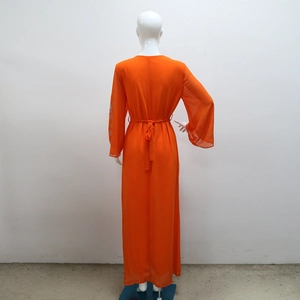 Détail d'une robe longue en mousseline orange avec des strass brillants aux poignets