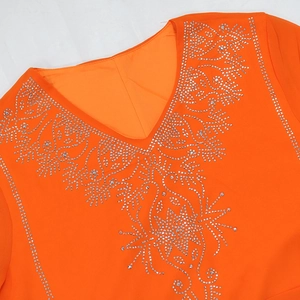 Détail du décolleté en V profond avec strass argentés sur une robe en mousseline orange
