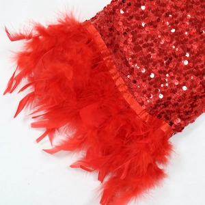 Dettaglio del tessuto con paillettes rosse e bordo in piume soffici su questo abito