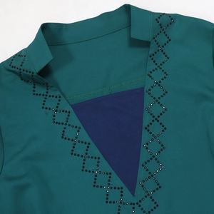 Detail of V-neckline featuring dark green fabric with rhinestone embellishments