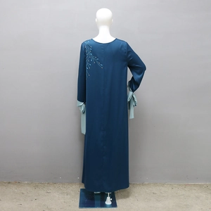 Détail du peignoir en satin avec broderie pailletée et rubans de soie verts sur les manches