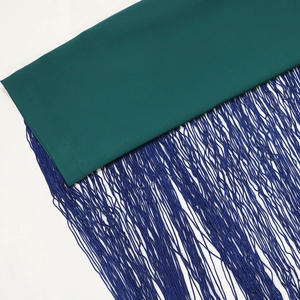 Detailed view of dark green robe hem featuring dense navy blue fringe and fine stitching