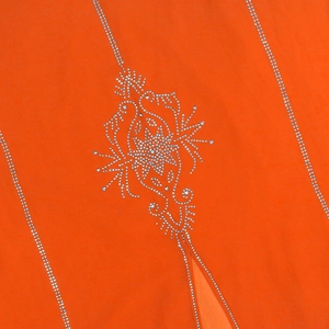 Détail de mousseline orange avec motifs floraux complexes en strass argentés