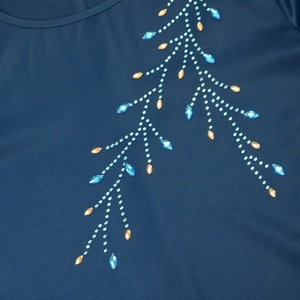 Détail de la robe en satin bleu canard avec motifs floraux de pierres bleues et dorées