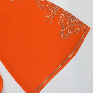 Détail d'une robe en mousseline orange vif avec des motifs floraux en strass argentés