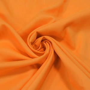 Détail macro du tissu mousseline orange vif avec une texture de drapé en spirale