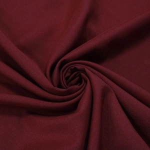 Gros plan sur un tissu mousseline bordeaux avec des plis doux et un drapé fluide