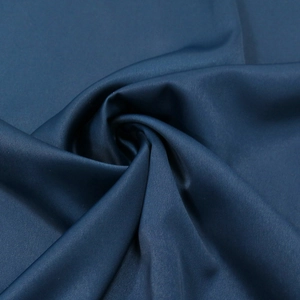 Gros plan du tissu satiné bleu foncé montrant un éclat soyeux et un drapé élégant