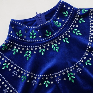 Detail of blue velvet dress neckline with green teardrop gems and white rhinestones