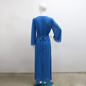 Détail de la robe longue en mousseline bleue avec nœud au dos et manches longues