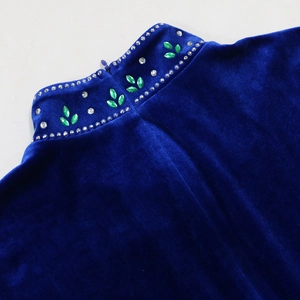 Macro shot of rhinestone-embellished mandarin collar on a luxury green velvet robe dress