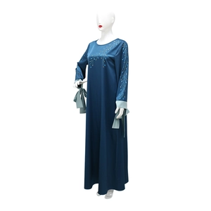 Détail de la robe en satin bleu marine avec sequins dorés et poignets vert clair