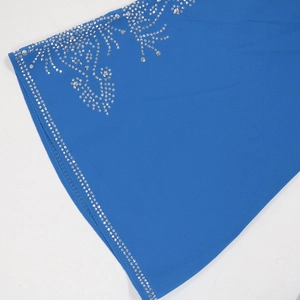 Détail d'une robe en mousseline bleu roi avec motifs floraux raffinés en strass