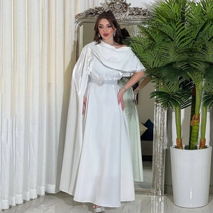 Detail of white satin evening gown featuring asymmetrical cape and rhinestone belt buckle