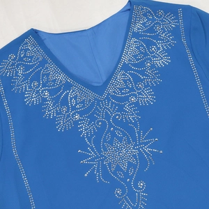 Détails des strass argentés brillants sur une robe bleu Klein avec un col en V