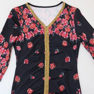 Dettaglio dello scollo a V con strass dorati e motivo floreale sull'abito elegante