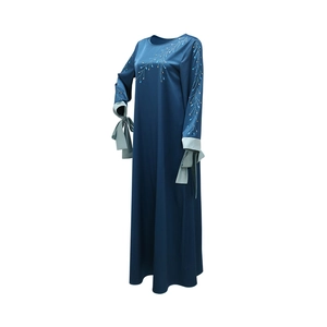 Détail des motifs en strass sur robe en satin marine avec poignets contrastés et nœuds