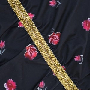 Vista macro della stampa floreale rosa e dei dettagli in paillettes dorate su tessuto nero