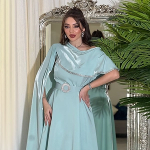 Detail of evening gown with satin fabric cape sleeves and large round rhinestone belt buckle