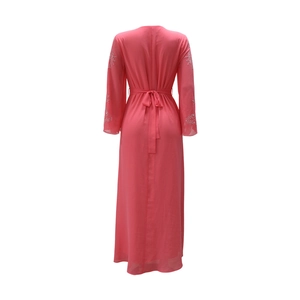 Détail de robe longue en mousseline rose avec broderie aux manches et nœud à la taille