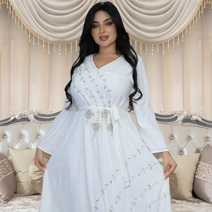 Detail of elegant white long sleeve dress featuring green and silver floral embroidery