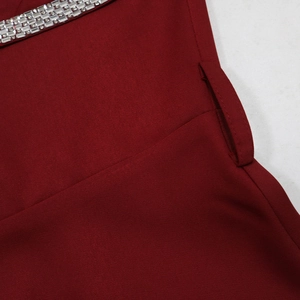 Detailed close-up of dark red slim evening gown fabric with crystal trim and belt loop