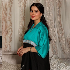 Detail of turquoise and black contrast long robe dress with ornate embroidered waist belt