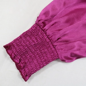 Detail of smocked elastic cuffs and puffed sleeves on a magenta satin velvet gown