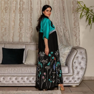 Detail of floral embroidery on the hem of a teal and black contrast maxi abaya dress