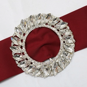 Close-up of sparkling rhinestone belt buckle on elegant burgundy satin evening dress