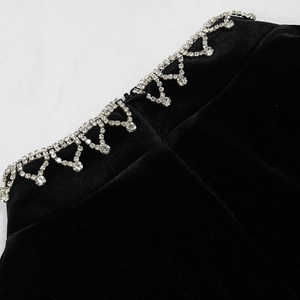Detailed view of luxury black velvet dress with shimmering rhinestone fringe trim