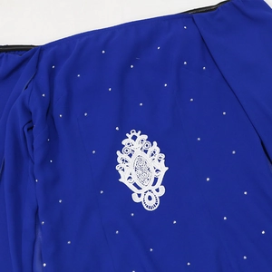Détail d'une robe en mousseline bleue avec dentelle blanche et strass scintillants
