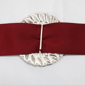 Close-up of a silver hollow leaf metal buckle with a deep red satin waist belt for gowns