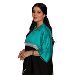 Detail of teal satin bodice with sequined braided trim and floral embroidery on dress