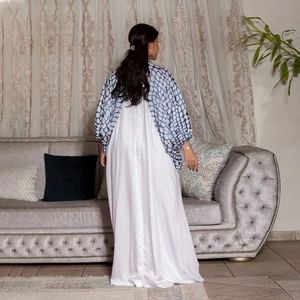 Detailansicht der Rückseite eines weißen Satin-Kleides mit blau gemustertem Cardigan
