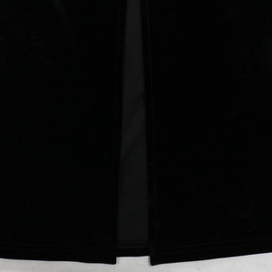 Detail view of the elegant high-slit hem on a black velvet fitted dress with inner lining