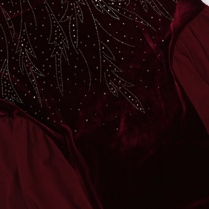 Macro view of burgundy velvet fabric with elegant silver rhinestone leaf pattern