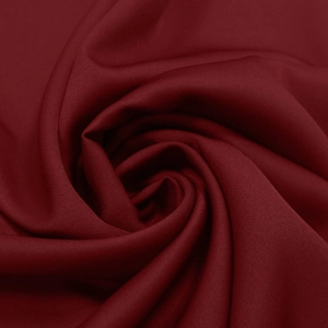 Macro shot of dark red textile fabric showing detailed texture and elegant pleat draping