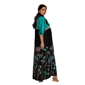 Detail of teal satin bodice and black skirt with intricate floral embroidery on kaftan