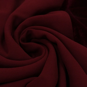 Detail of burgundy velvet chiffon fabric showing fine sand texture and elegant draping