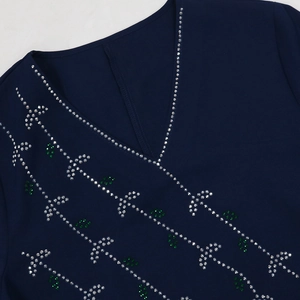 Detail of navy blue V-neck dress with intricate silver and emerald green rhinestone pattern