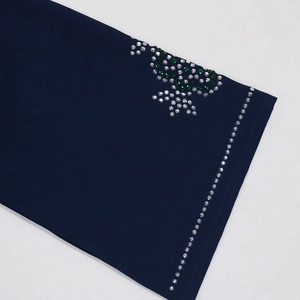Close-up of navy dress with sparkling white and green rhinestone floral pattern