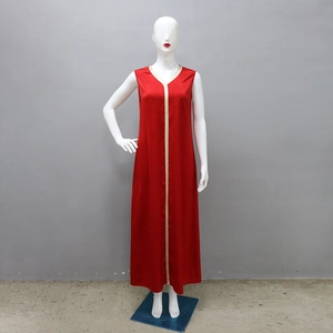 Détail d'une robe longue rouge sans manches avec bordure tressée or et blanc sur le col V