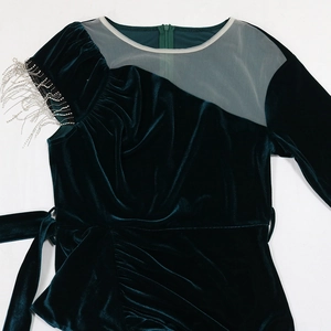 Detail of dark green velvet dress with mesh neckline and silver rhinestone fringe