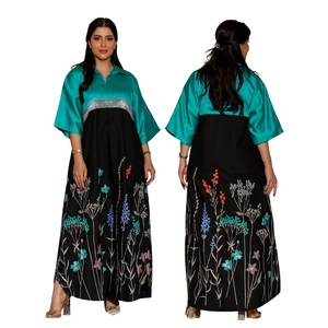 Detail of teal and black kaftan dress with colorful floral embroidery and silk texture