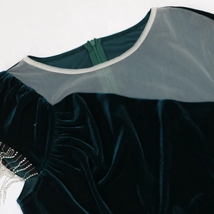 Detail of dark green velvet dress featuring rhinestone shoulders and silver chain fringes