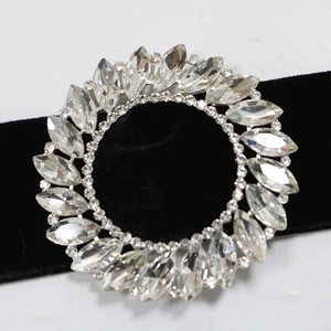 Close-up of a circular crystal brooch with marquise stones and black velvet ribbon detail