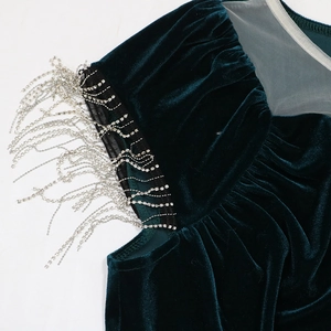 Detailed view of dark green velvet dress featuring elegant silver rhinestone fringe tassels