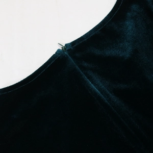 Close-up of the high-quality invisible zipper on the deep green velvet dress fabric