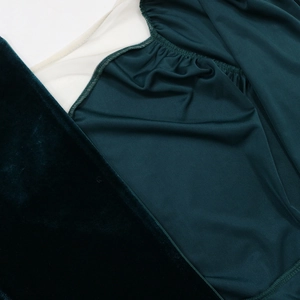 Macro shot of dark green velvet fabric with mesh stitching on slim-fit evening dress